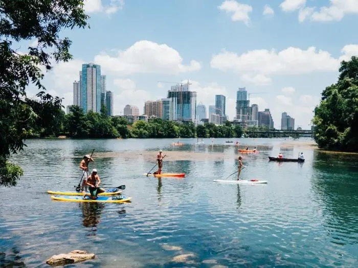A group of people canoeing in downtown Austin, TX with a glimpse of The Independent skyscraper in the background