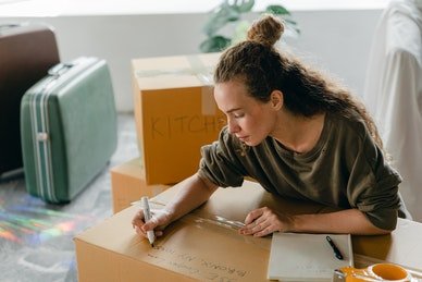 Woman Writing Down on a Moving Box | Spyglass Realty